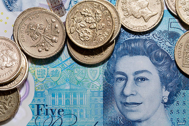 New Five Pound Note and One Pound Coins Swansea, UK: December 07, 2016: Close up of the new 2016 polymer five pound note with enhanced counterfeit resilience, showing the head of Queen Elizabeth II.  elizabeth ii photos stock pictures, royalty-free photos & images
