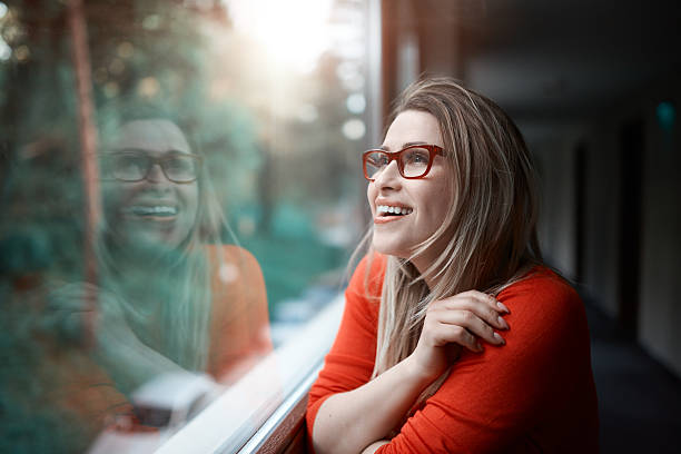 feeling so happy lifestyle shot of cheerful and carefree young woman looking on the window and smiling, enjoying the view. mesmerised stock pictures, royalty-free photos & images
