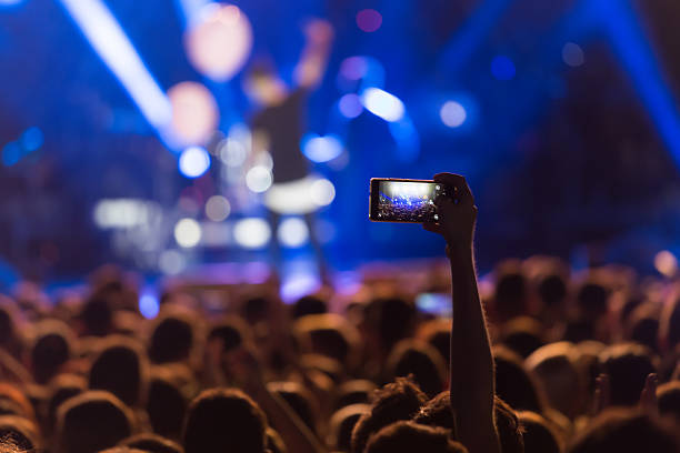 Hand with a smartphone records live music festiva