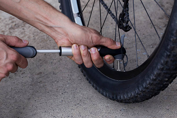 молодой человек надувает велосипедное колесо - bicycle bicycle pump inflating tire стоковые фото и изображения