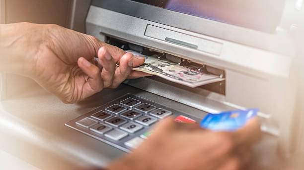 ATM machine, dollars and credit card Close up of woman's hand holding dollar banknotes from ATM machine and credit card in the other hand. atm photos stock pictures, royalty-free photos & images