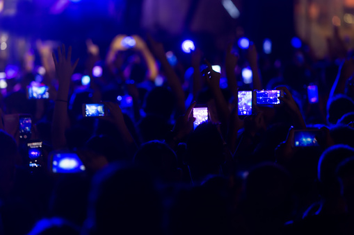 Hand with a smartphone records live music festival, Taking photo of concert stage, live concert, music festival, happy youth, luxury party, landscape exterior.