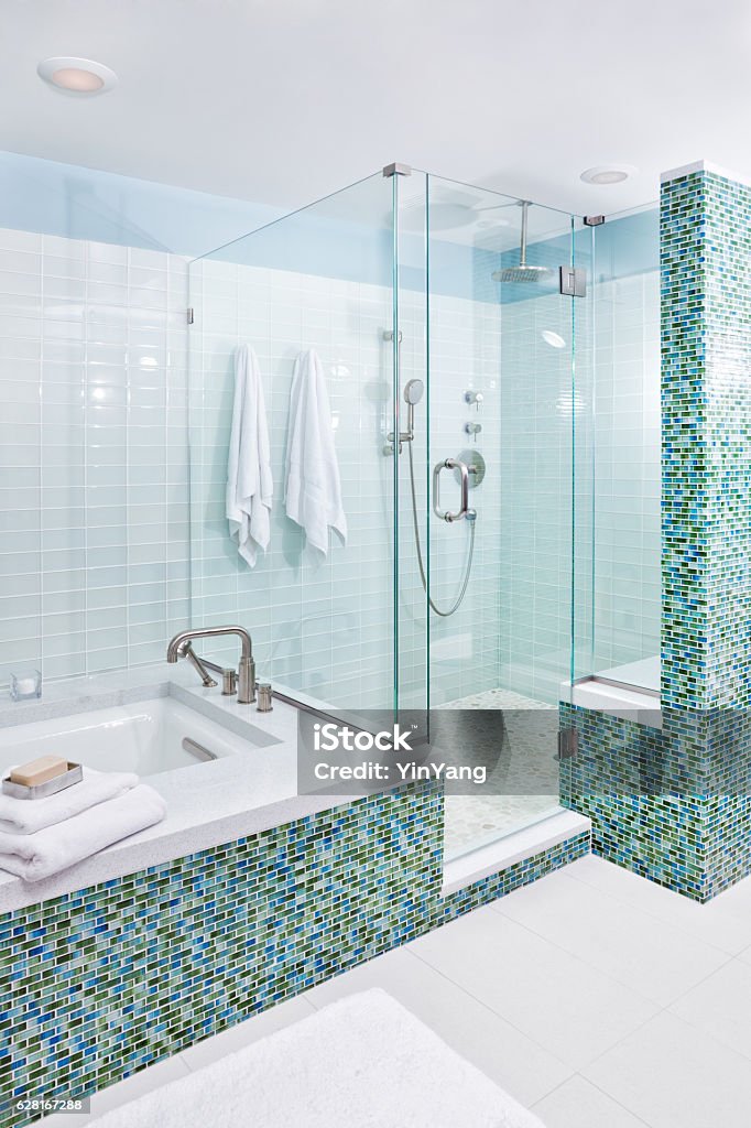 Contemporary Home Bathroom with Shower Stall, Tub and Glass Tiles Contemporary modern bathroom design featuring a conventional bathtub and a glass enclosed shower stall. Rain shower and conventional shower faucet. Glass tiles on the wall and ceramic tiles on the floor. Shower Stock Photo