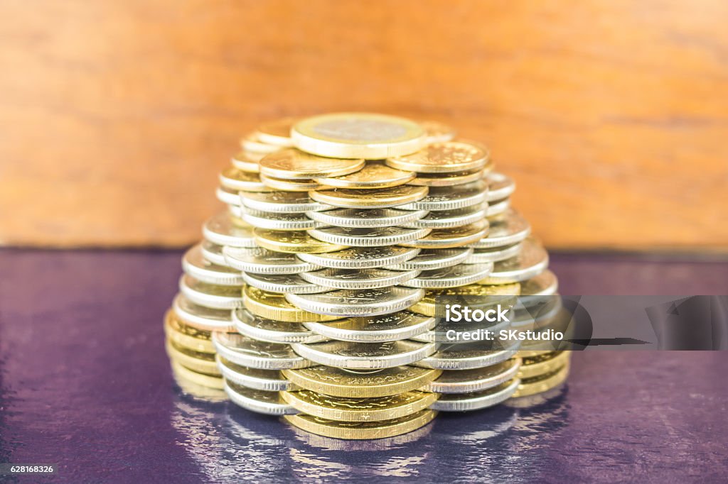 The pyramids of gold and silver coins on brown blurred The pyramids of gold and silver coins on brown blurred background. Business concept growth Finance. Achievement Stock Photo