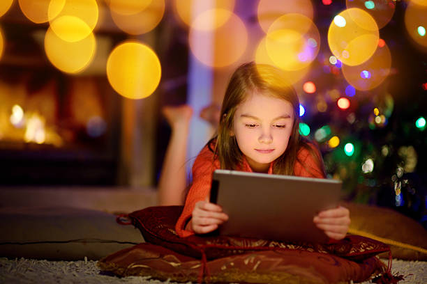 istock Adorable little girl using tablet pc by fireplace on Christmas 628169688