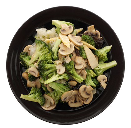 Chinese dish. Chinese food. Broccoli with chinese mushrooms in black plate isolated on white. Closeup.