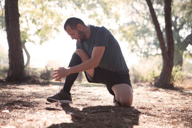 istock Young man tying his shoelaces in park 628172328