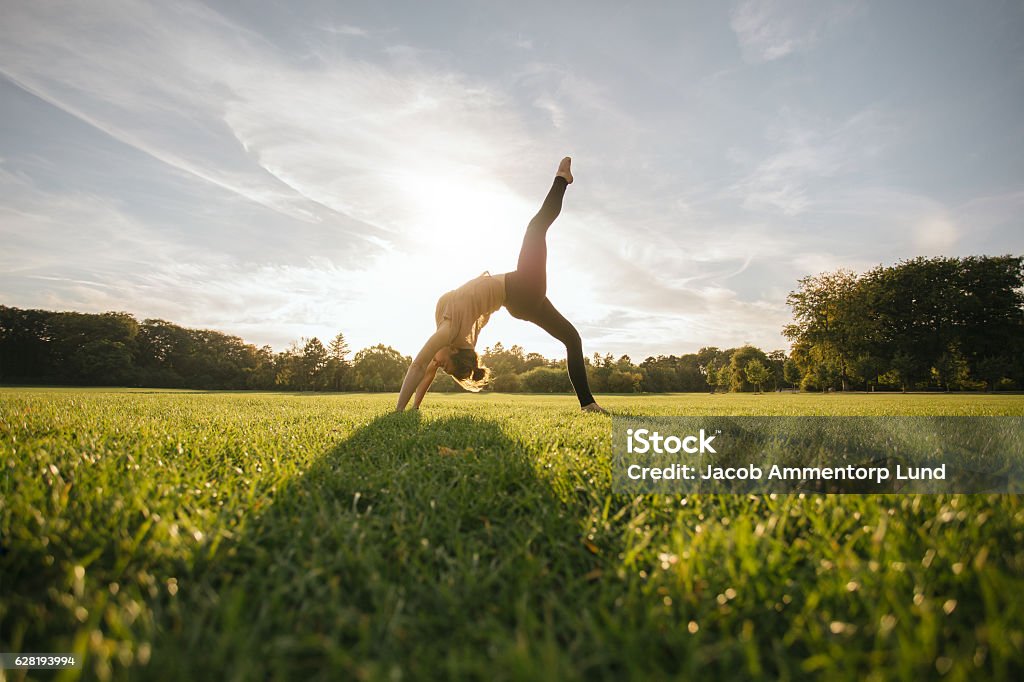 Healthy young woman doing yoga Healthy young woman doing yoga outdoors. Fit young female doing acrobatic exercise in park. Yoga Stock Photo