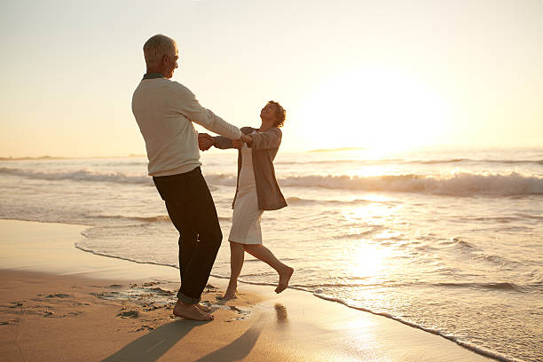 romántica pareja de ancianos disfrutando de un día en la playa - action senior adult lifestyles couple fotografías e imágenes de stock