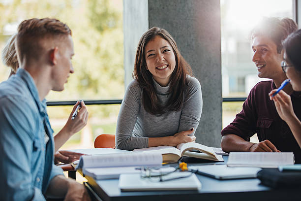 istock Smiling young woman with classmates in library 628194668