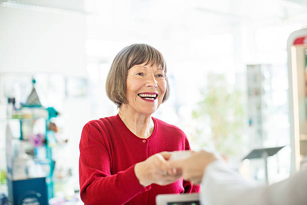 kobieta przyjmująca lek od farmaceuty - pharmacy pharmacist smiling pill zdjęcia i obrazy z banku zdjęć