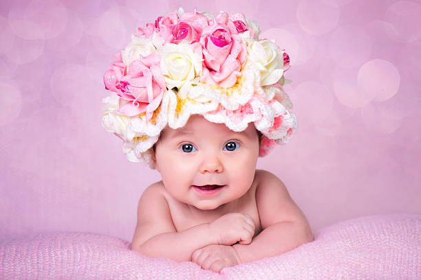 Newborn baby girl in the hat rose smiles. Portrait on stock photo