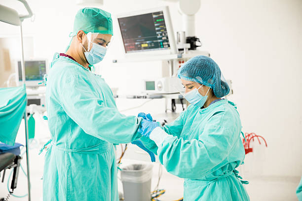 assistent hilft einem chirurgen im oder - nurse profile mask stock-fotos und bilder