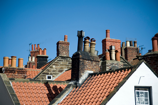 Rooftop view of a variety of different chimney pots on quaint cottages in the fishing village of Robin Hoods Bay, UK