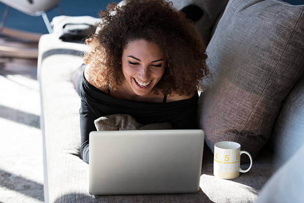 istock woman laughing as at her laptop on a sofa 628218012