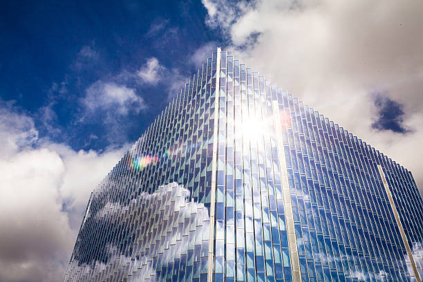 A view looking up, from the corner of the glassy cube shaped federal courthouse building at North Broadway and 1st Street in the downtown Los Angeles Civic Center, with dramatic clouds overhead and reflecting across the facade.