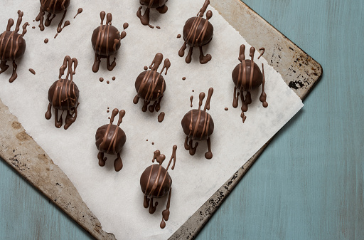 Chocolate covered cookie dough truffles on parchment and baking sheet