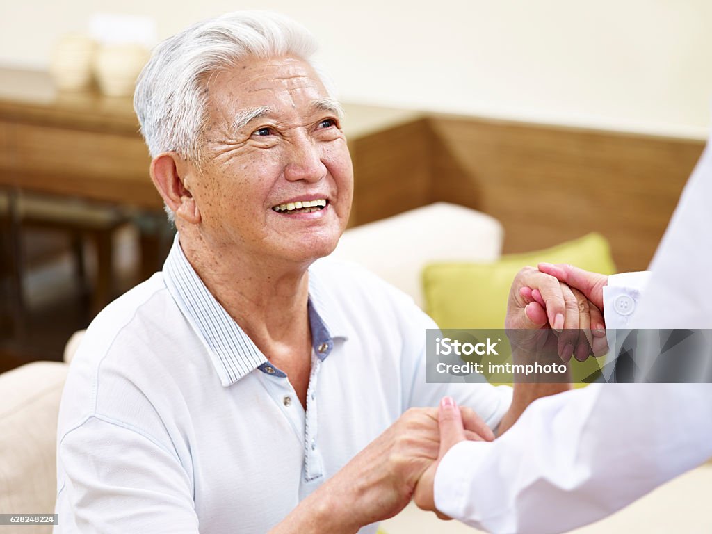 senior asian man getting helped happy and smiling senior asian man in his 80s getting helped by medical worker Senior Adult Stock Photo