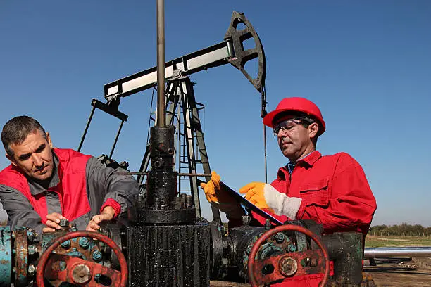 Engineers monitoring oil pumping unit at a oil field