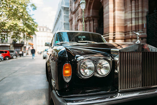 Luxury Rolls-Royce vintage limousine car in city Paris, France - September 12, 2016: Headlight and logotype of a exclusive Luxury Rolls-Royce car limousine parked in city during fashion wedding vip event waiting for passenger. Rolls-Royce Limited is a British car-manufacturing and, later, aero-engine manufacturing company founded by Charles Stewart Rolls and Sir Frederick Henry Royce on 15 March 1906 as the result of a partnership formed in 1904. rolls royce stock pictures, royalty-free photos & images