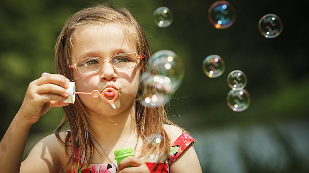 istock Little girl having fun blowing soap bubbles in park. 628279838