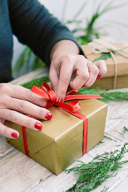 istock woman tying a red ribbon around a gift 628287724