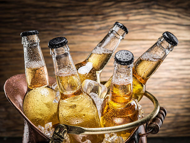 Cold bottles of beer in the brazen bucket. Cold bottles of beer in the brazen bucket on the wooden table. beer bottle photos stock pictures, royalty-free photos & images