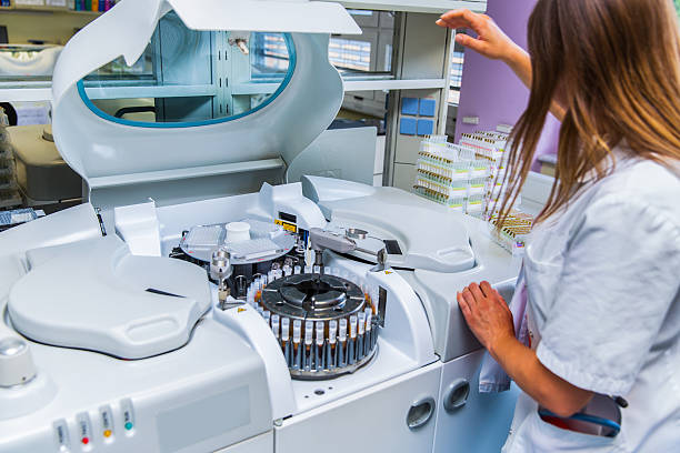 Lab scientist placing test tubes with blood samples in centrifuge Scene from a blood bank...Young Woman Lab scientist placing test tubes with blood samples in a centrifuge human centrifuge stock pictures, royalty-free photos & images