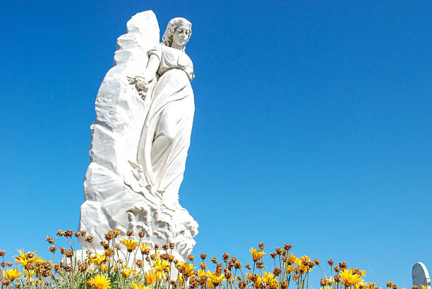 istock Statue of white lady looking over flowers 628298304