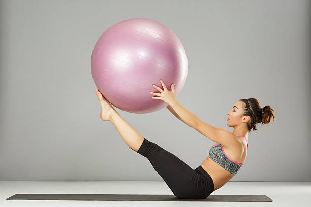 entrenamiento de estiramiento de pilates mujer practicando en una pelota de fitness - pilates fotografías e imágenes de stock