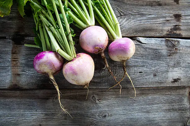 Photo of rustic organic turnips on genuine wood background for vegetarian food