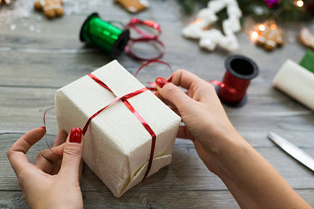 istock Woman wrapping modern Christmas gifts presents at home 628325708