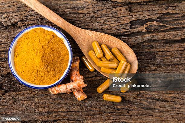 Turmeric Powder Capsule And Roots Curcumin On Wooden Plate Stock Photo - Download Image Now