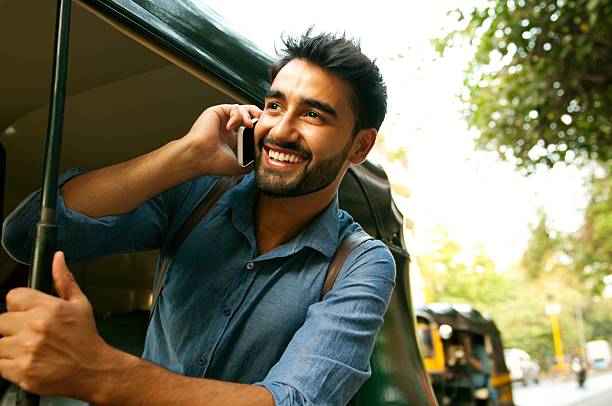 Calling from rickshaw. Picture of a smiling handsome man using his smartphone indian ethnicity lifestyle stock pictures, royalty-free photos & images