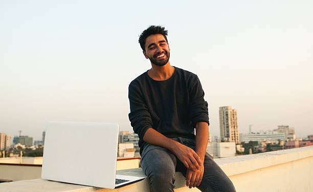 hombre sonriente con computadora portátil en la azotea. - men on roof fotografías e imágenes de stock