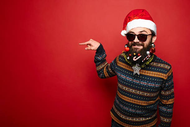 istock Young man in sunglasses and Santa hat pointing away 628333990