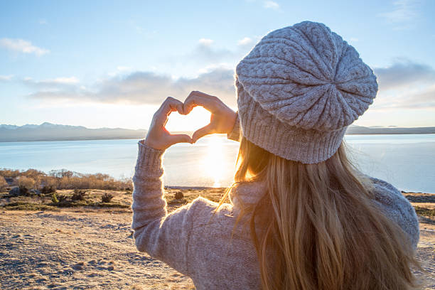 istock Young woman makes heart shape frame on lake 628334872