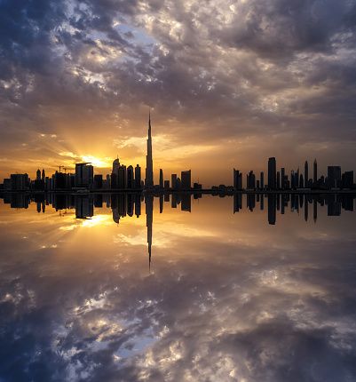 Fascinating reflection of tallest skyscrapers in Business Bay district during dramatic sunset. Downtown summer day. Construction built at evening time. Dubai, United Arab Emirates.