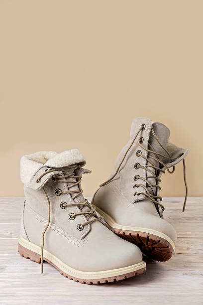 istock Bright leather winter boots on a light wooden background. 628347132