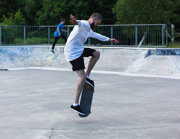 Man with beard mid skateboard trick stock photo