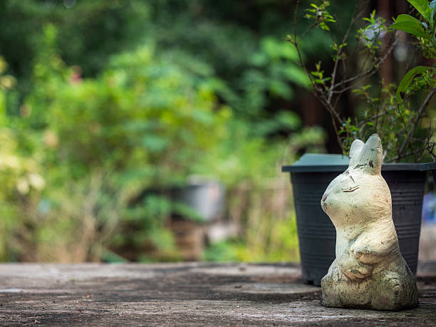 istock Rabbit statue is placed on a wooden floor,Garden background. 628347342