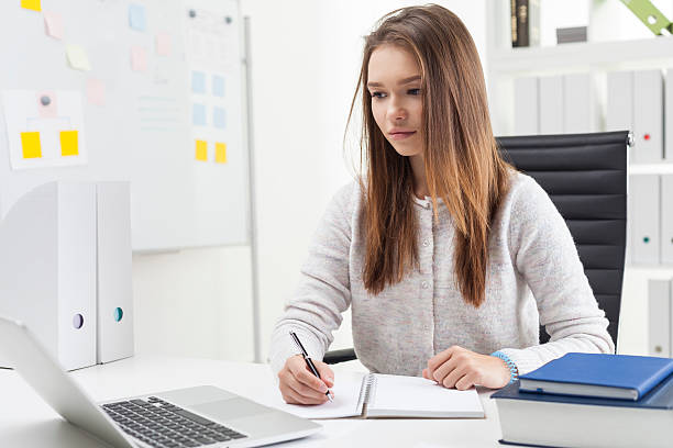 istock Centered secretary is writing and looking at laptop 628349056
