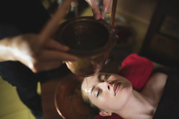 Pure Indulgence Young woman having an ayurvedic shirodhara treatment. ayurveda stock pictures, royalty-free photos & images