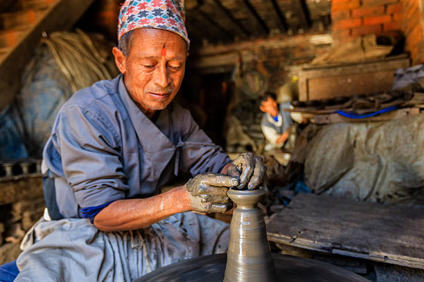Nepalese potter working in his workshop on pottery square in Bhaktapur. Bhaktapur is an ancient town in the Kathmandu Valley and is listed as a World Heritage Site by UNESCO for its rich culture, temples, and wood, metal and stone artwork.