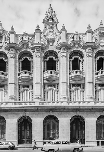 Havana, Cuba - October 11, 2016: Magnificent old Grand Theater  of Havana in center of the city, sandwiched between Capitolio (Cuban Parliament building) and old hotel of Inglaterra, on the main boulevard of Prado. This newly renovated colonial building was built in 1938 with grand hall that is now home of Cuban National Ballet. It also featured newly opened high end restaurant on the corner, overlooking Paseo De Marti vith the view of Capitol building. Beautiful example of Neo Classical architecture with variety of baroque style statues on the facade. People walking on the sidewalk. Local traffic passing by.