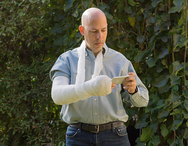 istock Young man with an arm cast texting on his phone 628359470