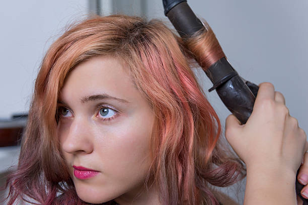 jovem usando ferro curling no cabelo - fashion shiny blond hair ringlet - fotografias e filmes do acervo