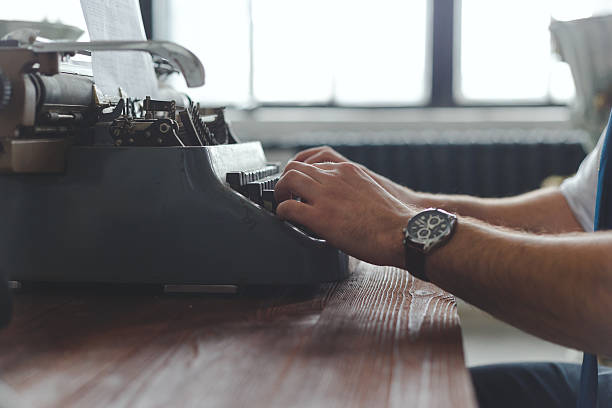 uomo che lavora su macchina da scrivere retrò alla scrivania in salotto - machine typewriter human hand typing foto e immagini stock