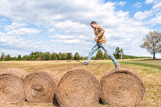 istock Young man jumping over hay roll bales 628362172