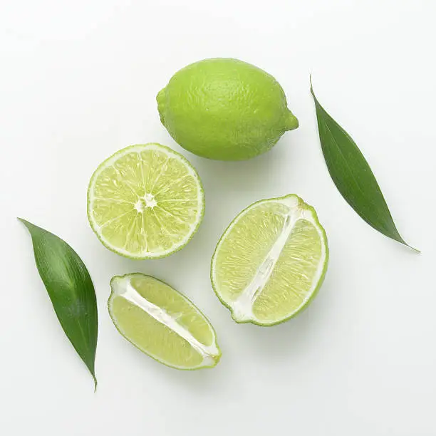some fresh limes with leaves on a white background